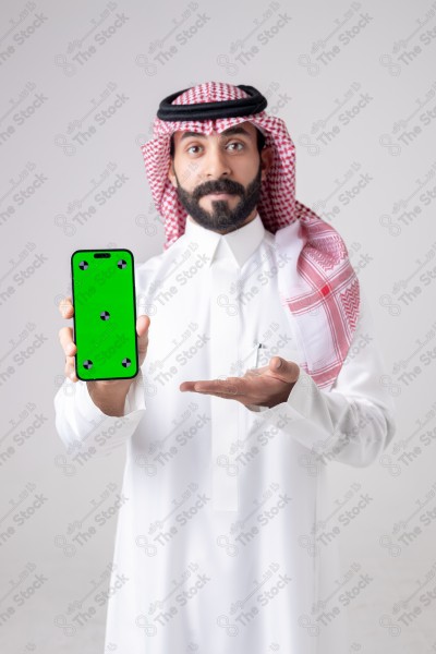 Portrait of a Saudi man holding a phone, pointing at the phone and making different expressions - green screen