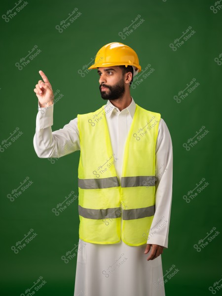 A man wearing a yellow safety vest and helmet pointing at something on a green background.
