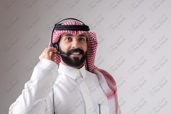 بورتريه رجل سعودي يلبس سماعة الرأس ويقوم بالتواصل عبر السماعة - خدمة العملاء ، مكالمة هاتفية