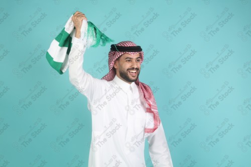 شاب سعودي يرتدي الزي السعودي ممسك شال بيده بتعابير وجه و يدين تدل على السعادة والحماس ، كأس العالم