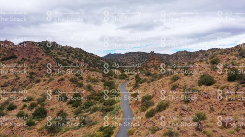 A group of cumulus clouds overlapping the green Sarawat mountains