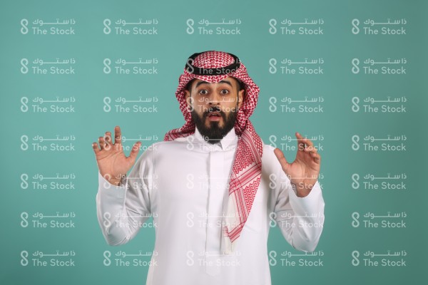 بورتريه شاب متفاجئ يرتدي ثوب أبيض ويعبر بيديه عن مدى تعجبه