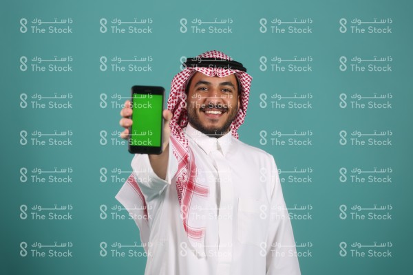 شاب سعودي يستخدم الجوال ويرتدي الزي السعودي