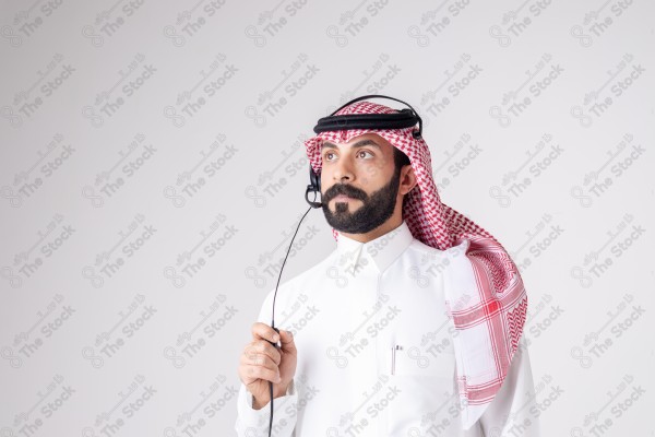 بورتريه رجل سعودي يلبس سماعة الرأس ويقوم بالتواصل عبر السماعة - خدمة العملاء ، مكالمة هاتفية