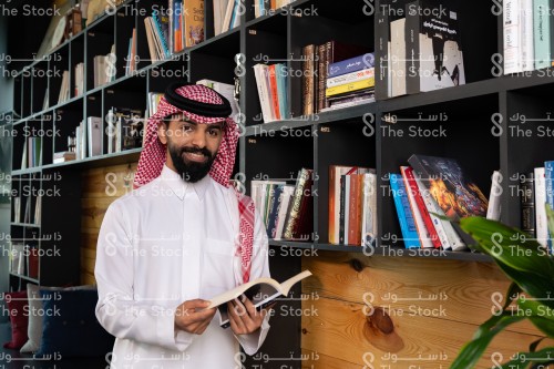 رجل سعودي يستمتع بقراءة وتصفح  الكتب في المكتبة