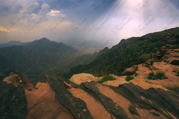 Aerial shot of a series of rocky mountains at sunset and the clouds overlapping between them, nature in Saudi Arabia, sunset