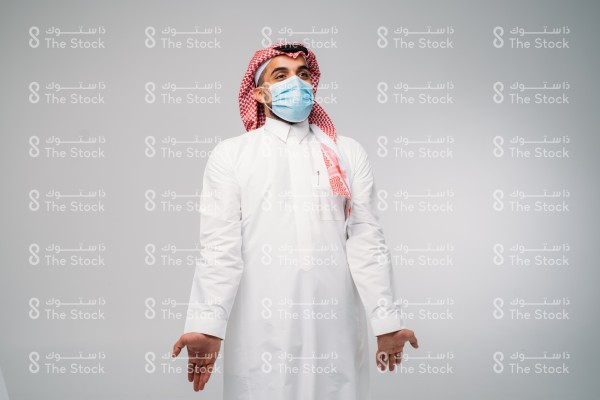 تفاعل رجل يرتدي الكمامة بالزي السعودي الرسمي على خلفية رمادية