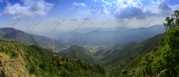 Aerial shot of a series of rocky mountains and the overlapping of clouds between them, nature in Saudi Arabia, the sky is clear