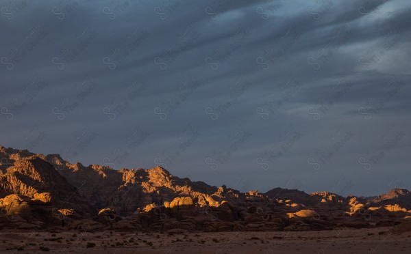 لقطة لشروق اشعة الشمس على جبال محافظة العلا التاريخية نهارًا، سلسلة من الجبال الصخرية.