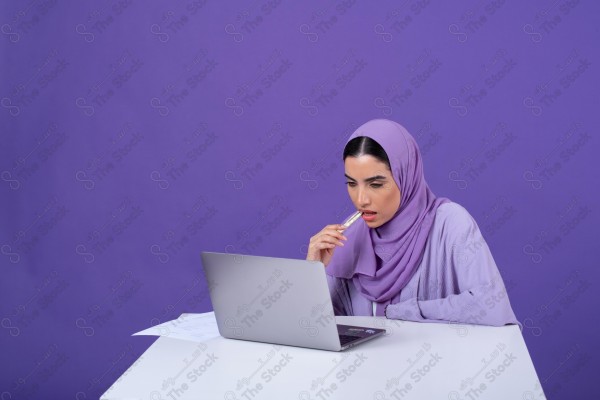 Portrait of a young Saudi woman wearing an abaya and hijab, holding a pen and thinking, against a purple background