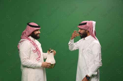 رجل سعودي يرتدي الزي السعودي التقليدي يقدم لضيفه القهوة السعودية في أحد المناسبات