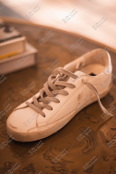 A white sneaker with gray laces on a wooden table.