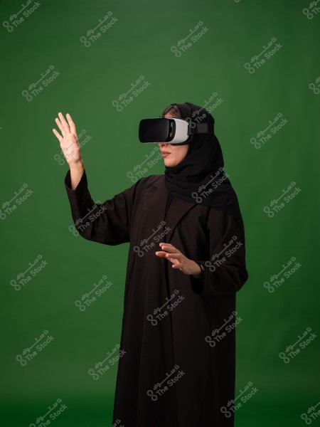 امرأة ترتدي نظارة واقع افتراضي وتقوم بحركات بيديها بخلفية خضراء.