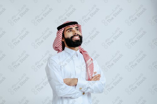 بورتريه رجل سعودي يرتدي الزي الرسمي التقليدي على خلفية بيضاء يقوم بعمل اشارات بيديه وهو مبتسم ، صور تذكارية ، توثيق لحظة سعيدة.