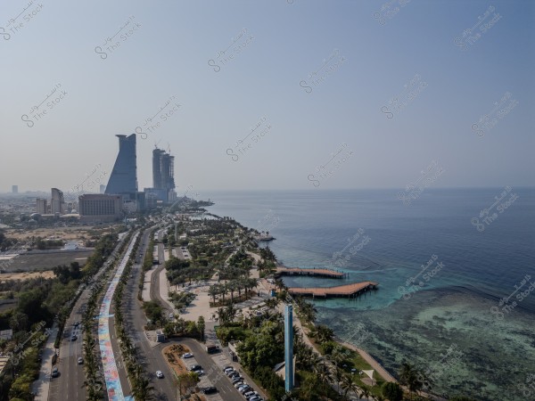 Aerial view of the Corniche Road in Jeddah, Saudi Arabia, with tall buildings on the left and the Red Sea on the right.