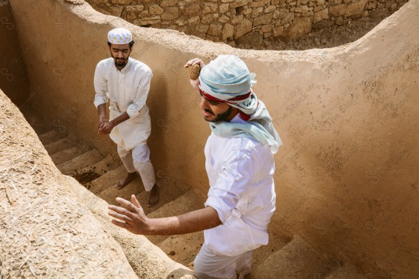 لقطة لرجلان سعوديان يعملان في بناء البيت قديم يرتدون الزي السعودي التقليدي الذي يمثل التراث الشعبي ، يوم التأسيس، الثقافة السعودية