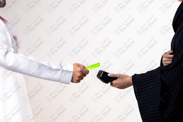 Portrait of a Saudi man holding a card and making automatic payments on a white background