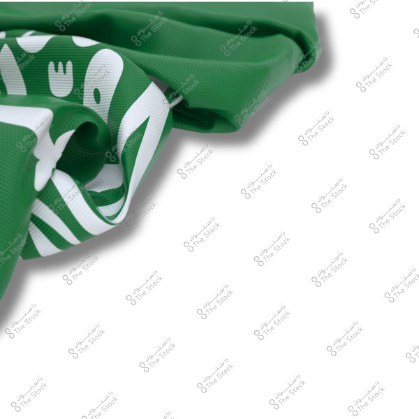 An image showing a section of a green flag with white inscriptions, displaying part of the Shahada folded artistically.