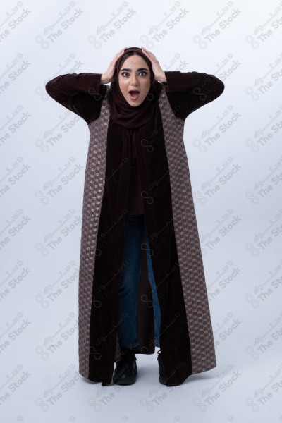 Portrait of a young Saudi woman wearing an abaya and hijab, with a smiling facial expression, standing against a white background