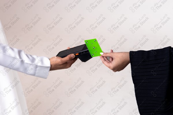 Portrait of a Saudi woman holding a card and making automatic payments on a white background