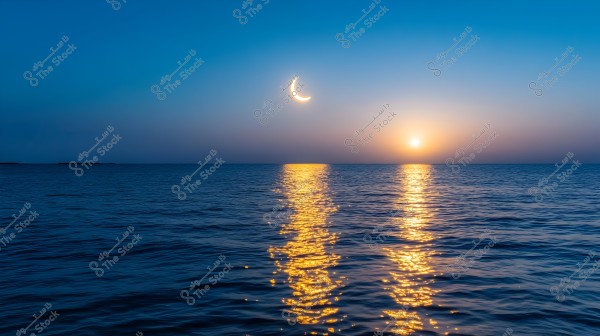 A beautiful seascape at sunset showing the reflective light playing on the water\'s surface. A crescent moon is visible in the deep blue sky, while the sun sets on the horizon leaving a warm glow illuminating the water.