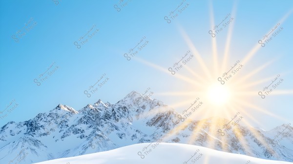 A scenic view of a snow-covered mountain under a clear blue sky. The bright sun is shining from the right, casting long radiant beams across the mountain peaks.