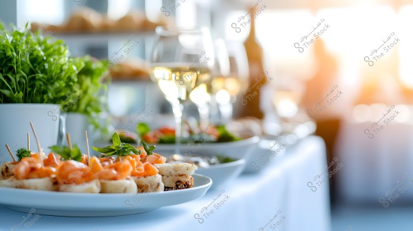 An image of an elegant dining table featuring plates with smoked fish garnished and toothpicks, with green plants visible in the background. There are also wine glasses filled with white wine on the table, illuminated by natural light from the windows.