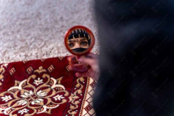 A shot of a Saudi woman whose eyes are reflected from the mirror wearing the traditional Saudi dress that represents the folklore, the day of foundation, the Saudi culture.