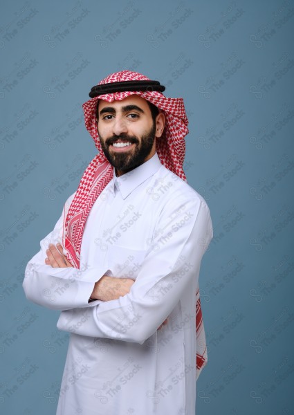 Portrait of a Saudi young man wearing the Saudi dress, and happiness and joy appearing on his features, against a heavenly background