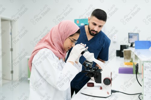 Saudi doctor in a hospital works in a laboratory, a medical team uses a microscope to examine a blood sample, and works in the field of health, providing medical consultations and medical health services.