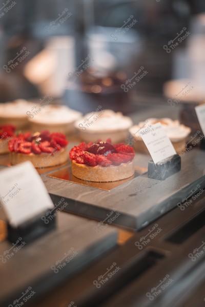 Display of desserts in a shop window, featuring a raspberry yogurt tart.