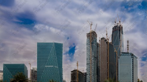 A shot showing the buildings and landmarks of the financial center under construction for the city of Riyadh, in front of it a group of residential houses, and the sky appears overcast with clouds.