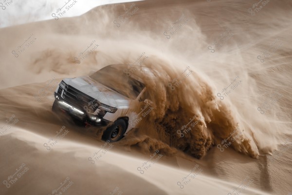 A white SUV driving at high speed through sand dunes, kicking up a cloud of sand around it. The scene is set in a vast open desert, with sand sloping on the sides.