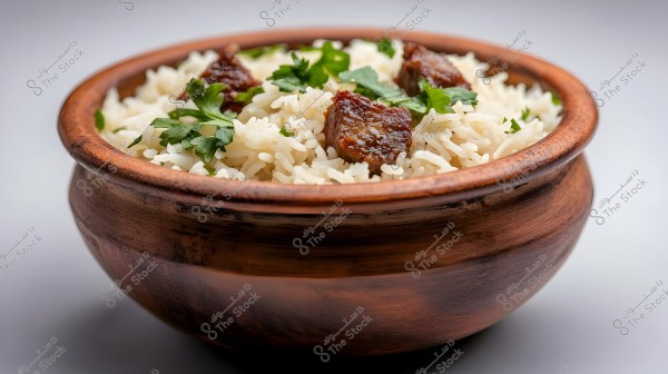 Image of a wooden bowl filled with cooked white rice, brown meat pieces, and green parsley leaves. The dish looks appealing and well-garnished on a white surface.
