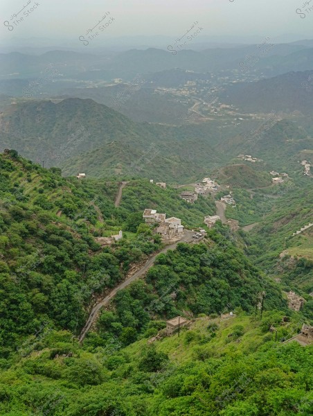 A natural landscape of green mountains in Saudi Arabia, with scattered houses on the hills and among dense forests. Winding roads traverse the mountains, highlighting the rugged terrain of the area. The sky is slightly overcast, adding a sense of calm and tranquility to the scene.
