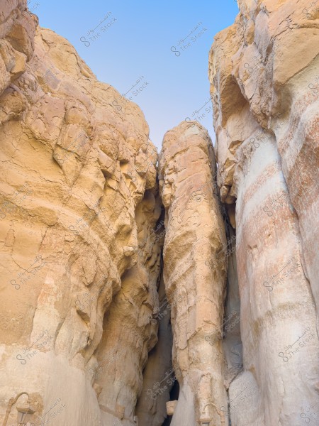 صورة لمنحدرات صخرية شاهقة الشكل, بألوان تتراوح بين البني الفاتح والبيج, مع سماء زرقاء صافية في الخلفية. التكوين الصخري يظهر تفاصيل النسيج الطبيعي مع شق مرتفع.\r\n جبل القاره الاحساء \r\n-