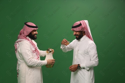 رجل سعودي يرتدي الزي السعودي التقليدي يقدم لضيفه القهوة السعودية في أحد المناسبات