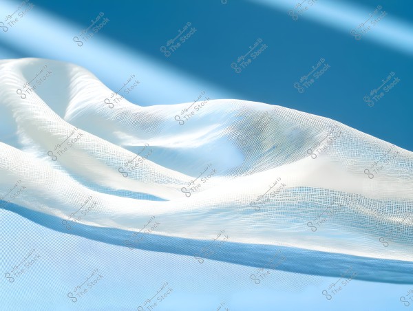An image showing a piece of sheer white fabric rippling against a smooth blue background. The light creates shimmering effects on the fabric, highlighting its fine details and mesh-like pattern. The image represents the movement of the fabric with the interplay of light and shadow.