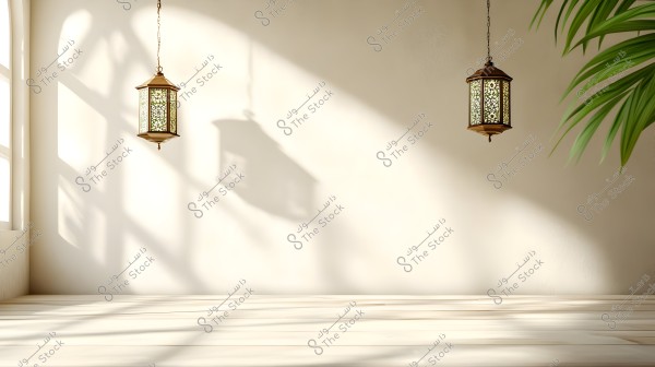 Two hanging lanterns on a light beige wall, casting their shadows. The window on the left allows natural light to enter. There is a portion of a green-leafed plant on the right side of the image.