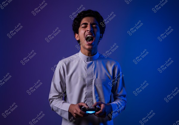 A portrait of a person wearing a traditional garment with a high collar, possibly from Saudi Arabia or other Gulf countries. The individual is holding a gaming controller and appears to be engaged and expressive. The background is lit with blue and purple lighting, giving the image a dramatic feel.