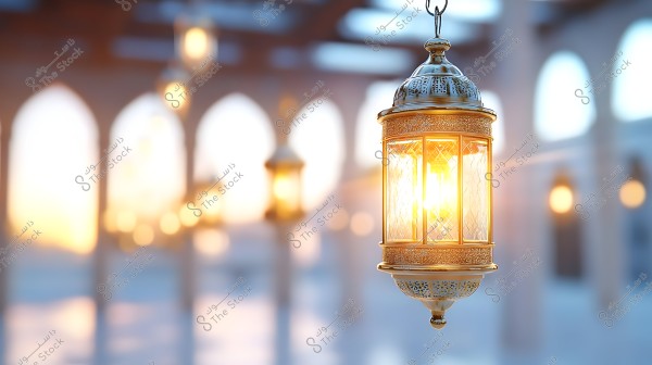 A lit golden Arabic lantern hangs prominently in the foreground. In the blurred background, there are arches and columns illuminated by other hanging lanterns, creating a serene and beautiful atmosphere that blends light and shadow.