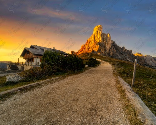 A shot of a landscape of the Italian Alps, with bumpy roads surrounded by residential houses, the Alps mountain range, roads and slopes.