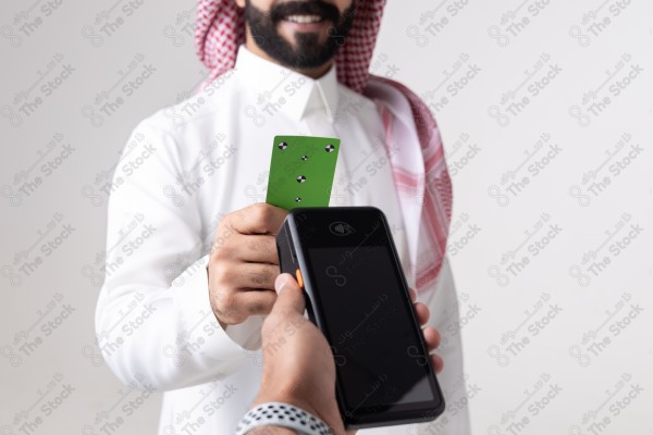 Portrait of a Saudi man holding a card and making automatic payments on a white background