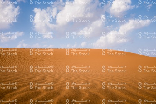 السماء الزرقاء و الغيوم المتقطعة على الرمال الذهبية في صحراء خريص شرق المملكة العربية السعودية