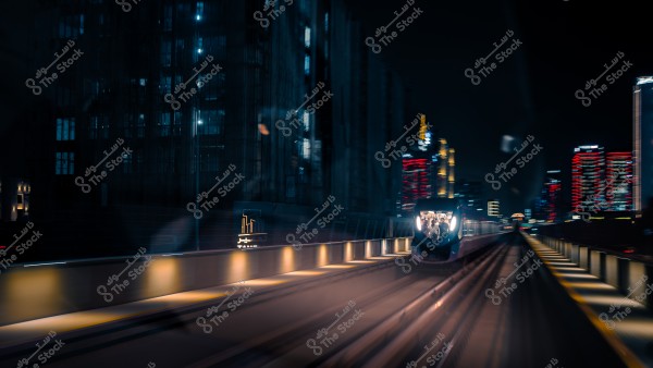 مترو يسير بسرعة ليلاً في مدينة مضاءة, بجوار مبانٍ عالية بإضاءة نيون ملونة.