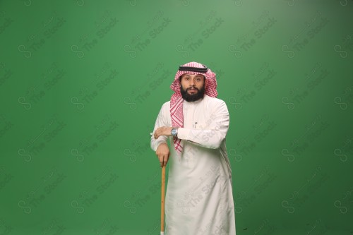 بورتريه رجل سعودي يرتدي الزي السعودي التقليدي يتكئ على العصا أثناء أداء رقصة المزمار الحجازية