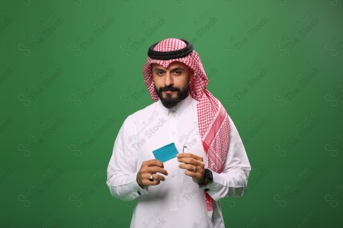 رجل سعودي على خلفية خضراء مبتسم يحمل بطاقة الصراف جاهز للتسوق