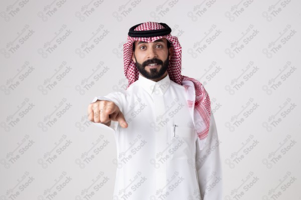 بورتريه رجل سعودي يقف على خلفية بيضاء ويشير بيده اتجاه معين