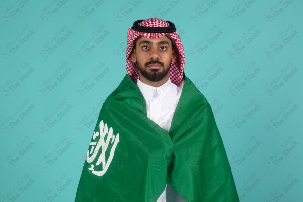 بورتريه رجل سعودي يحمل العلم السعودي على كتفه احتفالاً باليوم الوطني