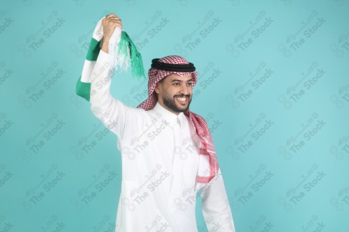 شاب سعودي يرتدي الزي السعودي ممسك شال بيده بتعابير وجه و يدين تدل على السعادة والحماس ، كأس العالم